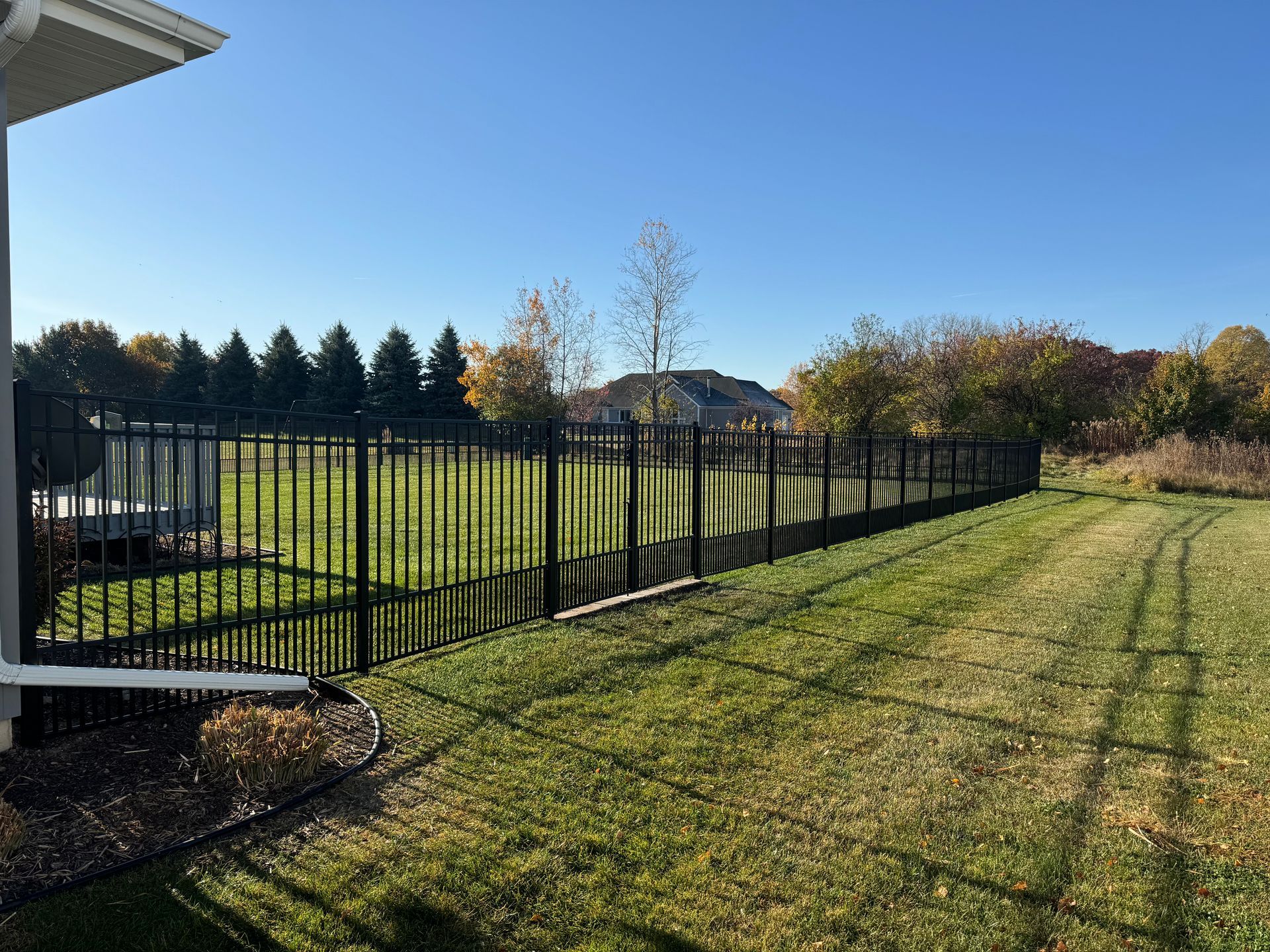 A black metal fence surrounds a lush green field.
