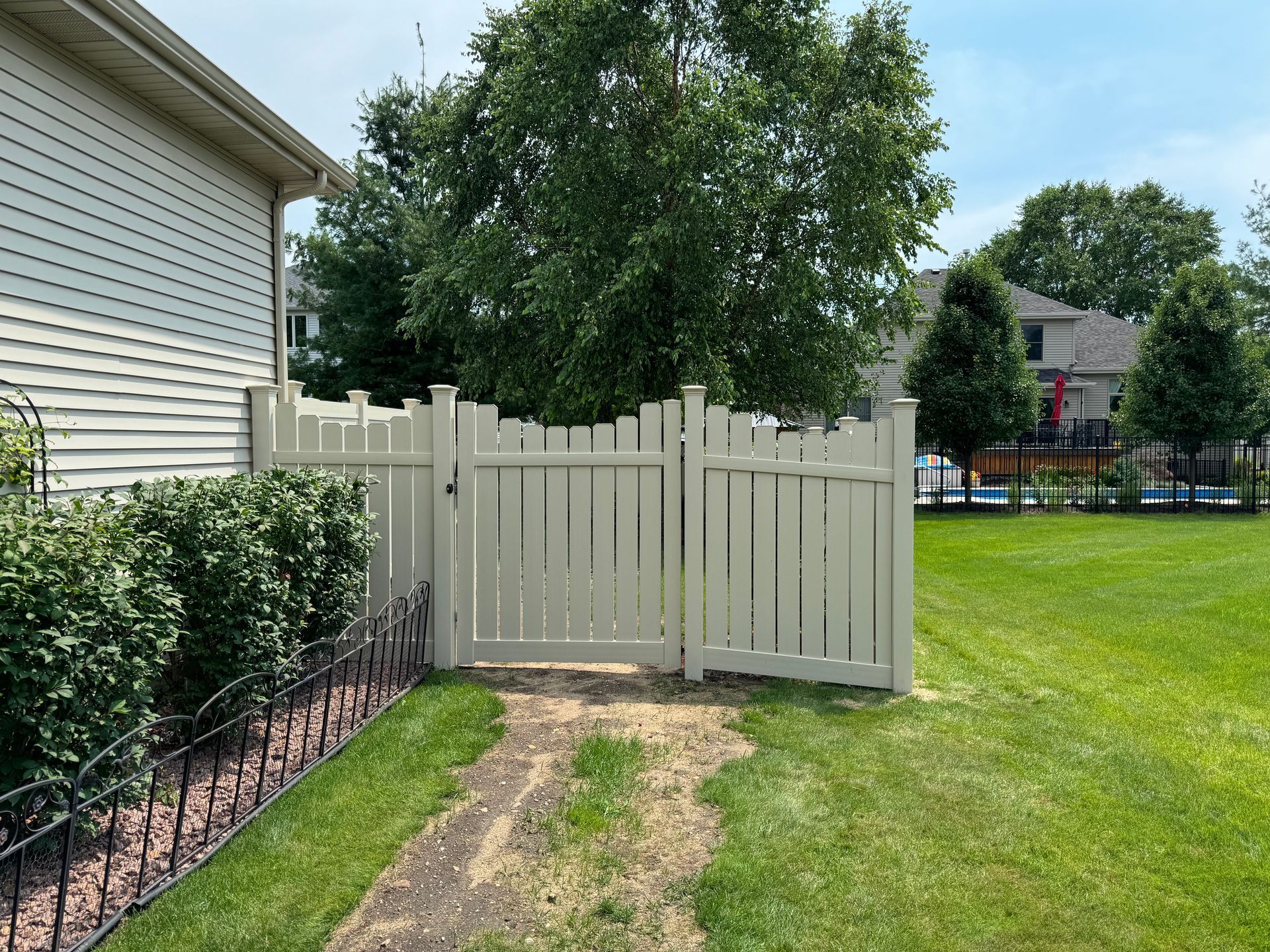 A white fence with a gate in the backyard of a house.