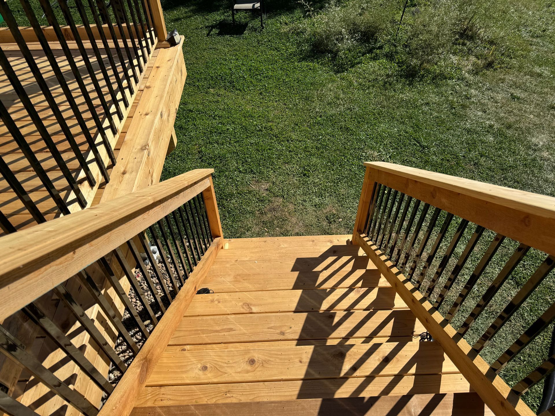 A wooden deck with stairs leading up to it and a metal railing.