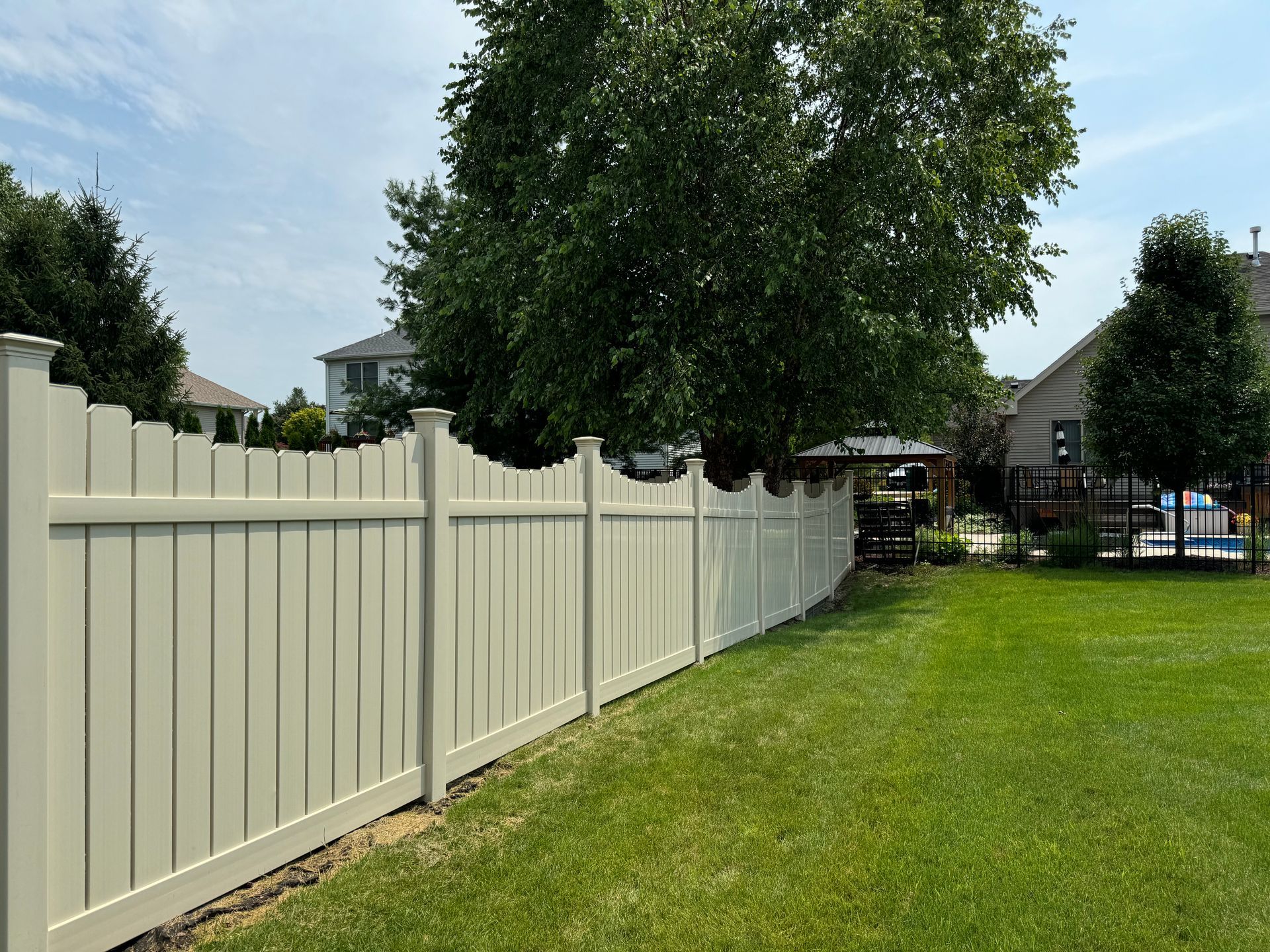 A white vinyl fence surrounds a lush green yard.