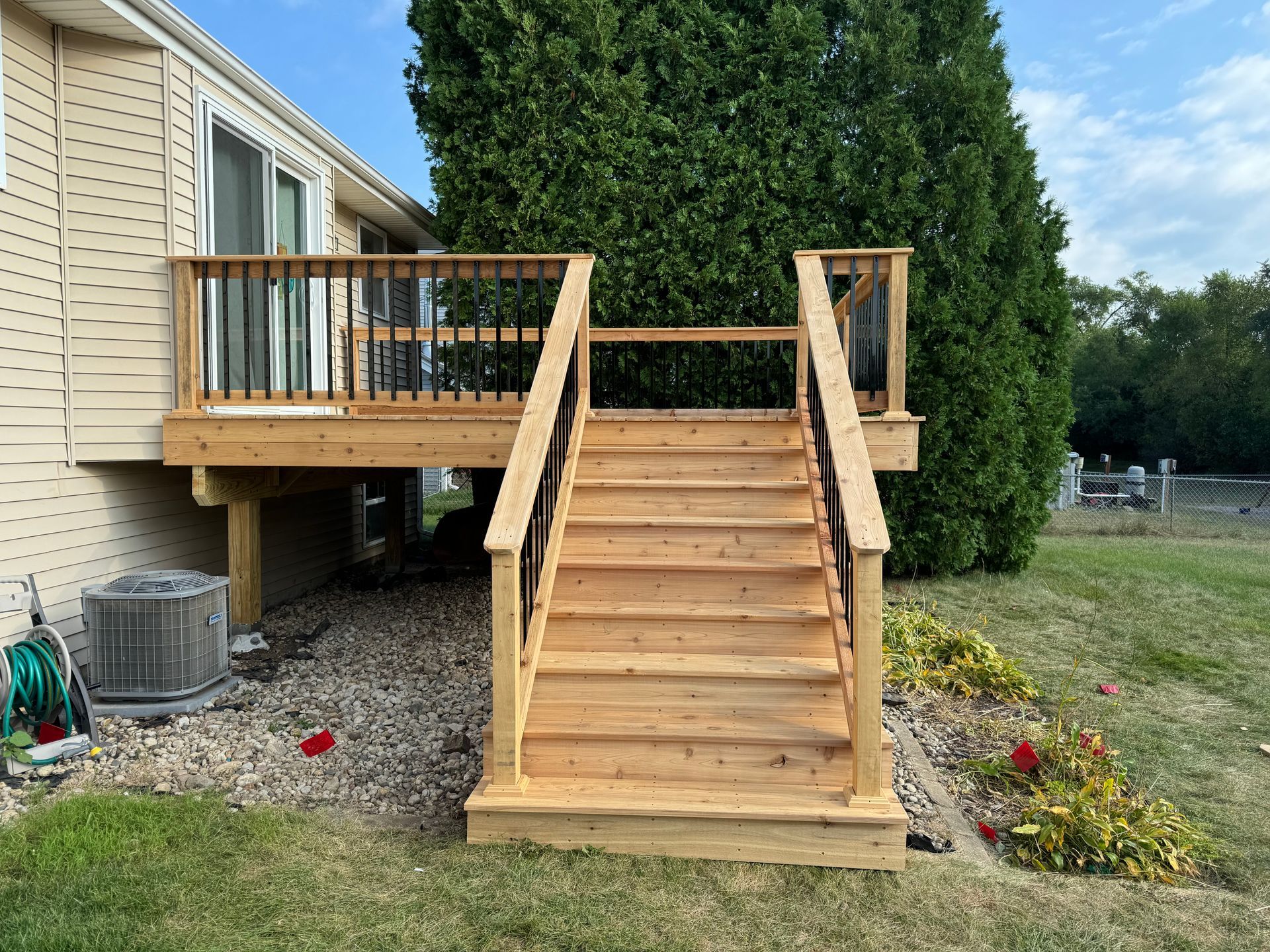 A wooden deck with stairs leading up to it is in front of a house.
