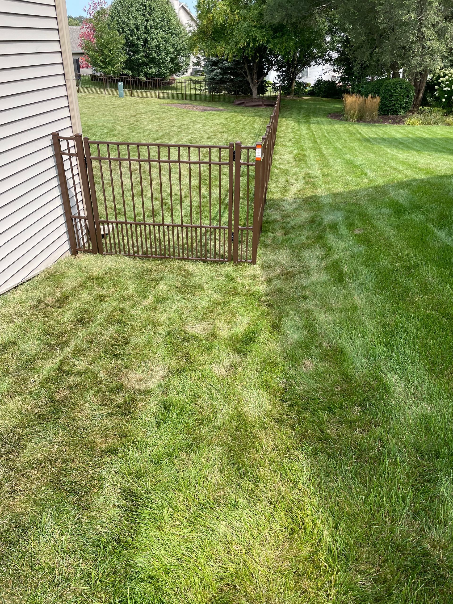 A backyard with a fence and a gate in the middle of it.