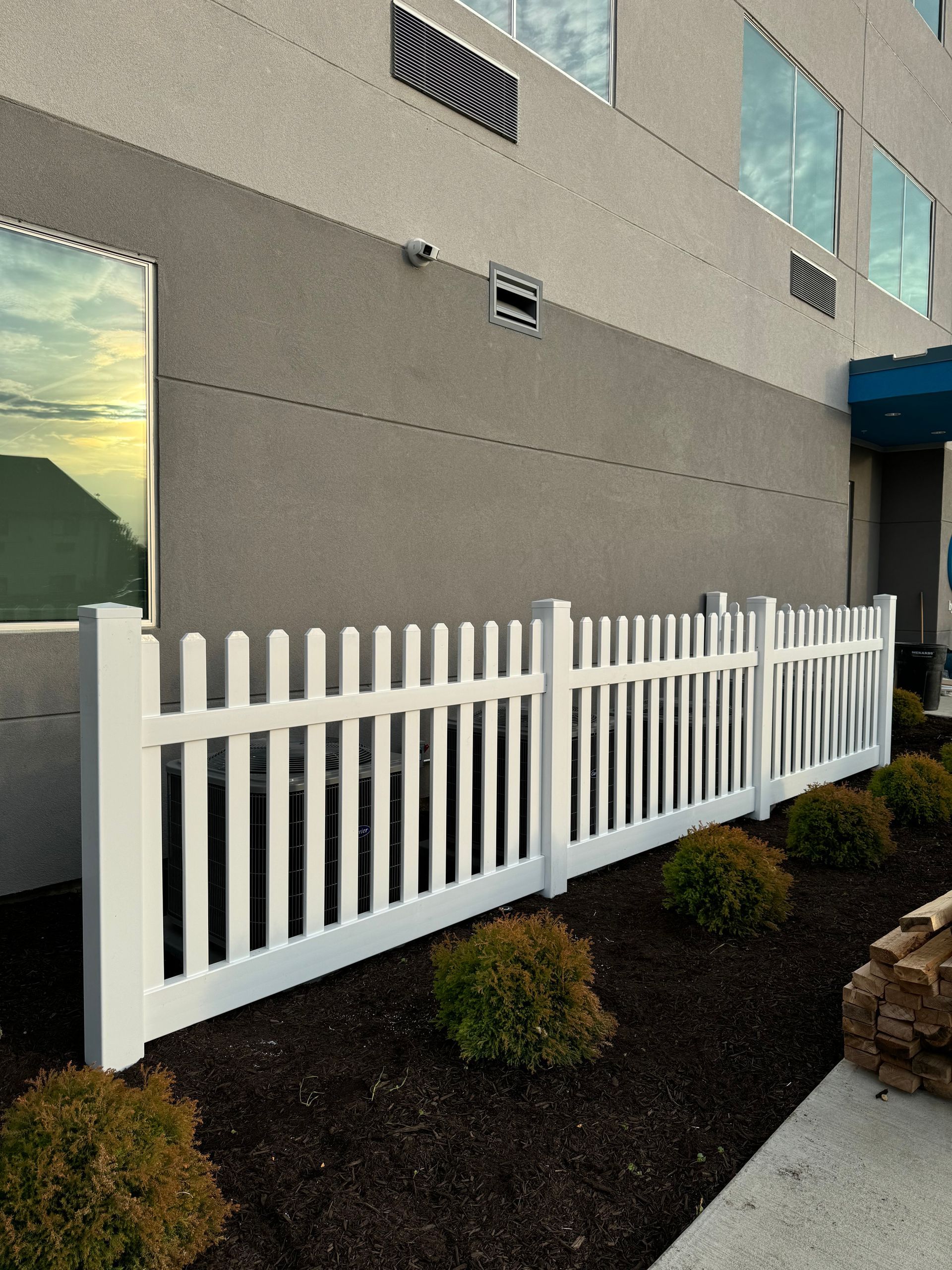 A white picket fence is in front of a building.