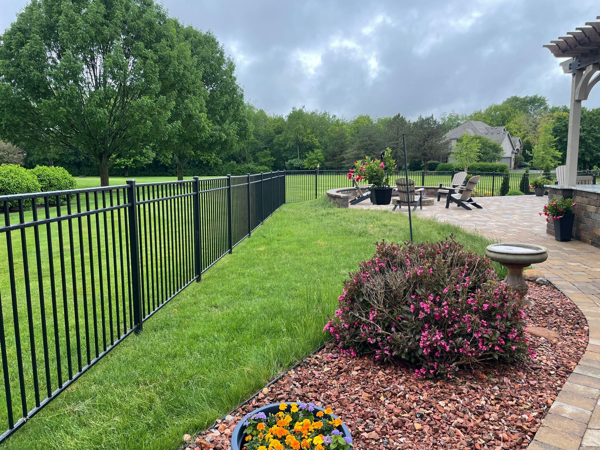 A fence surrounds a lush green yard with a patio in the background.