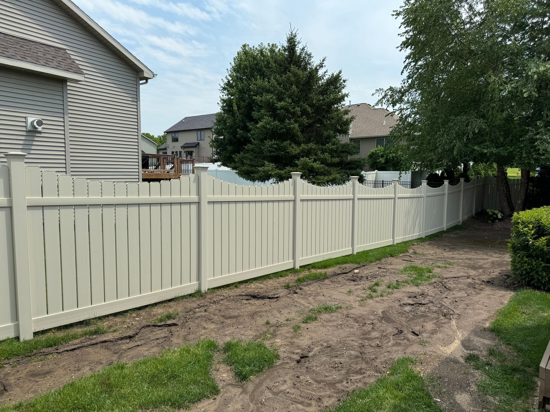 There is a white fence in the backyard of a house.