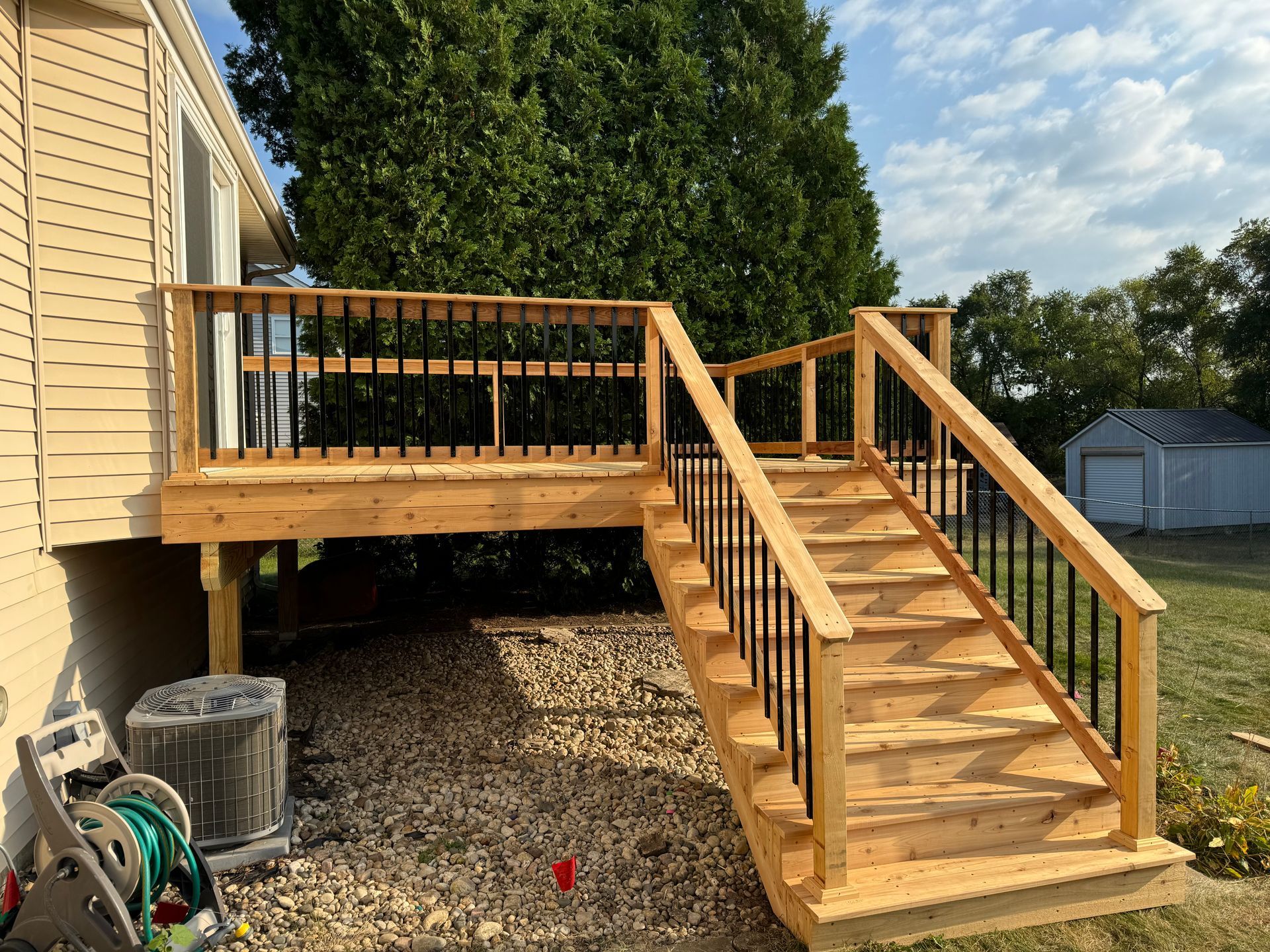 A wooden deck with stairs leading up to it next to a house.