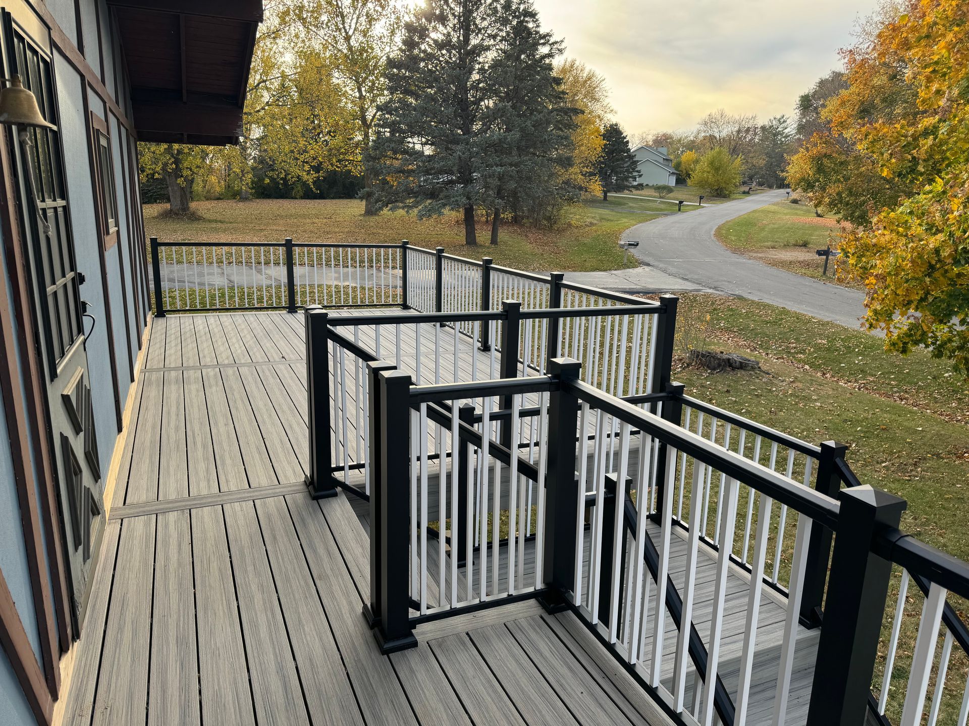 A large wooden deck with a black and white railing.