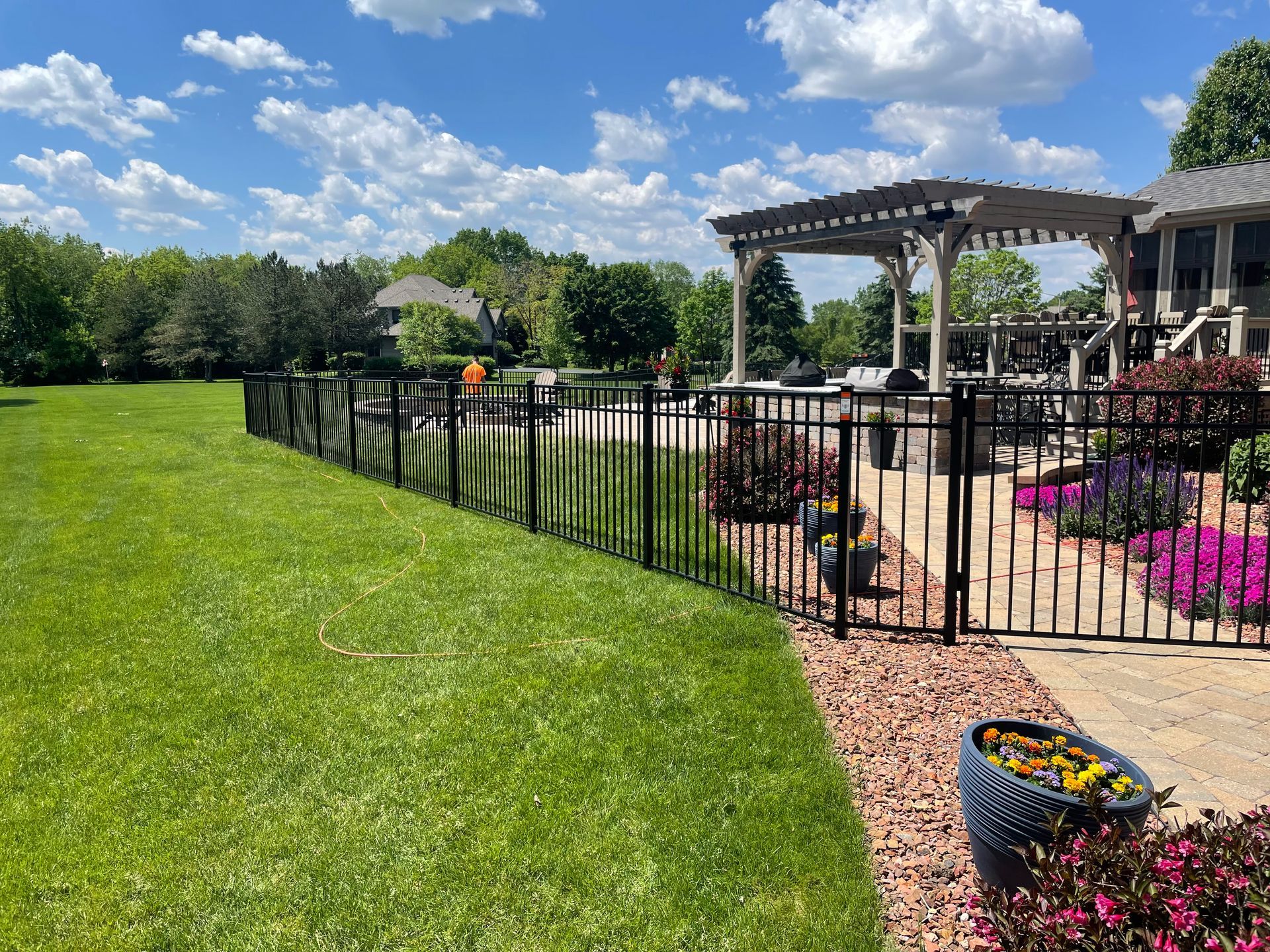 A black fence surrounds a lush green lawn in a backyard.