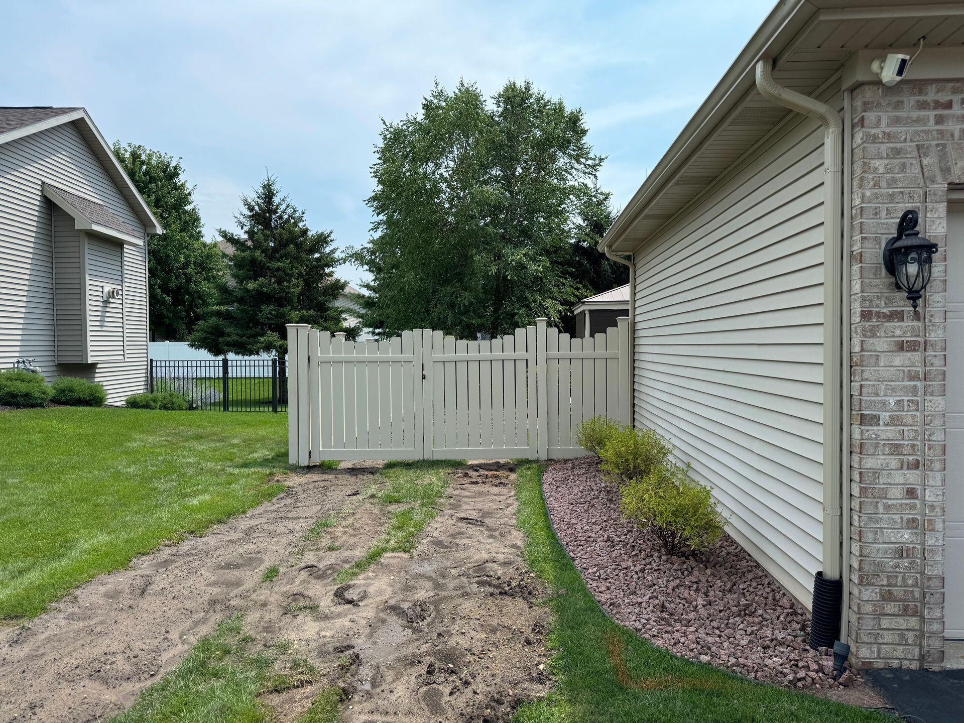 A house with a white fence and a dirt path leading to it