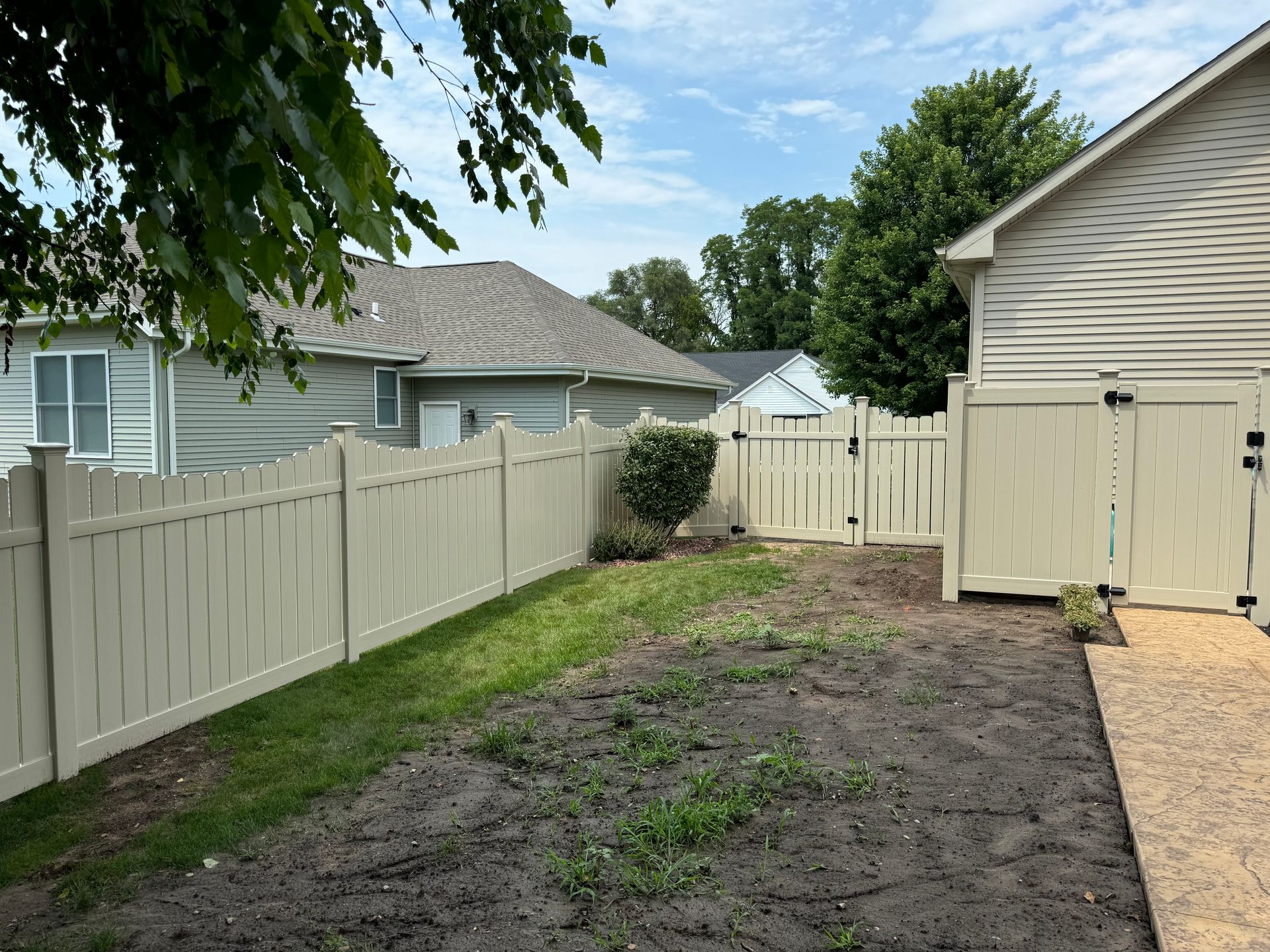 The backyard of a house with a white fence and a gate.