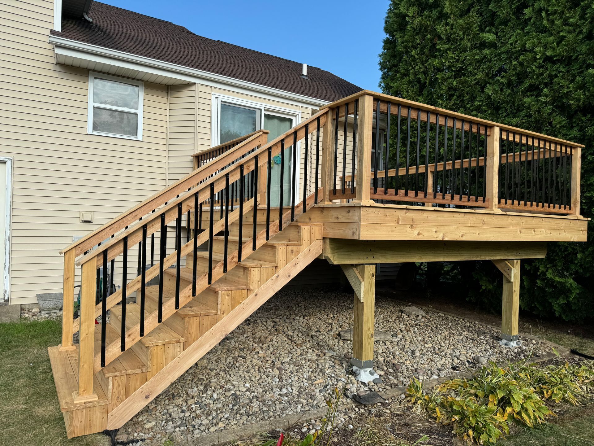 A wooden deck with stairs leading up to it is in front of a house.