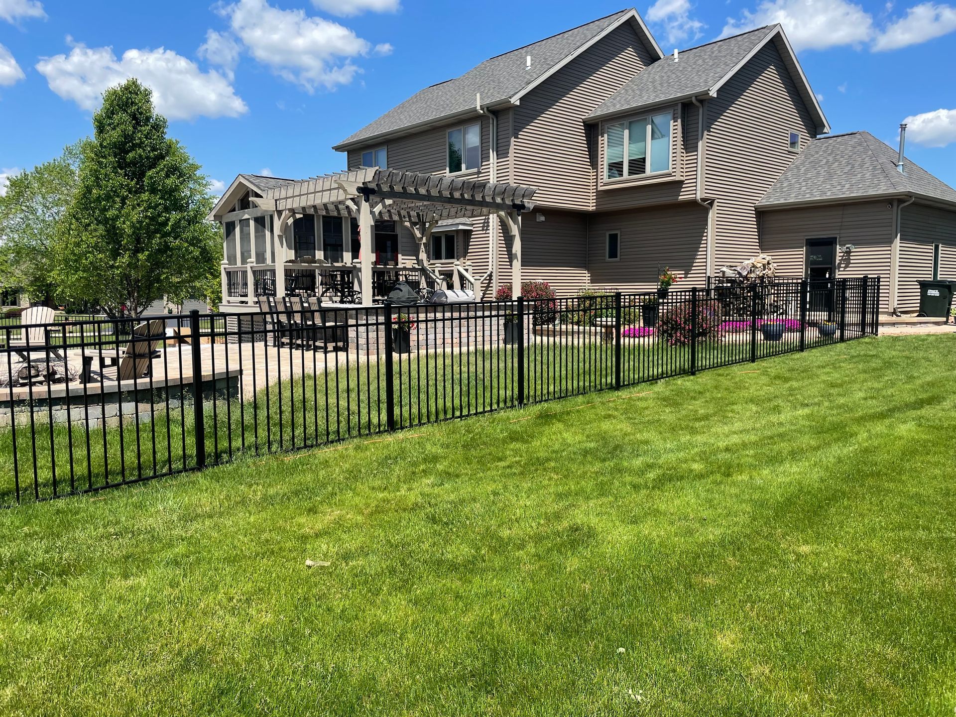 A large house with a fence around it and a large lawn in front of it.