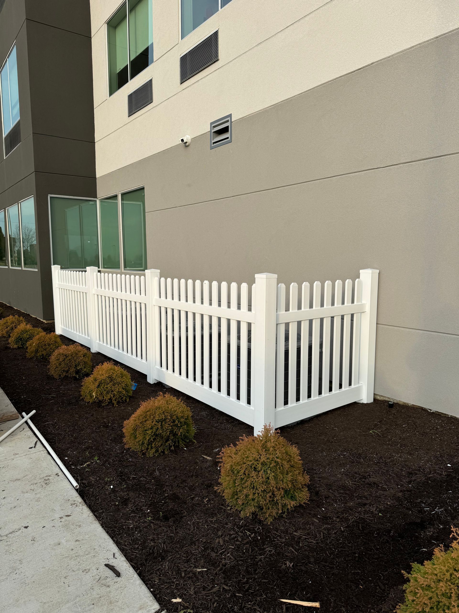 A white picket fence is in front of a building