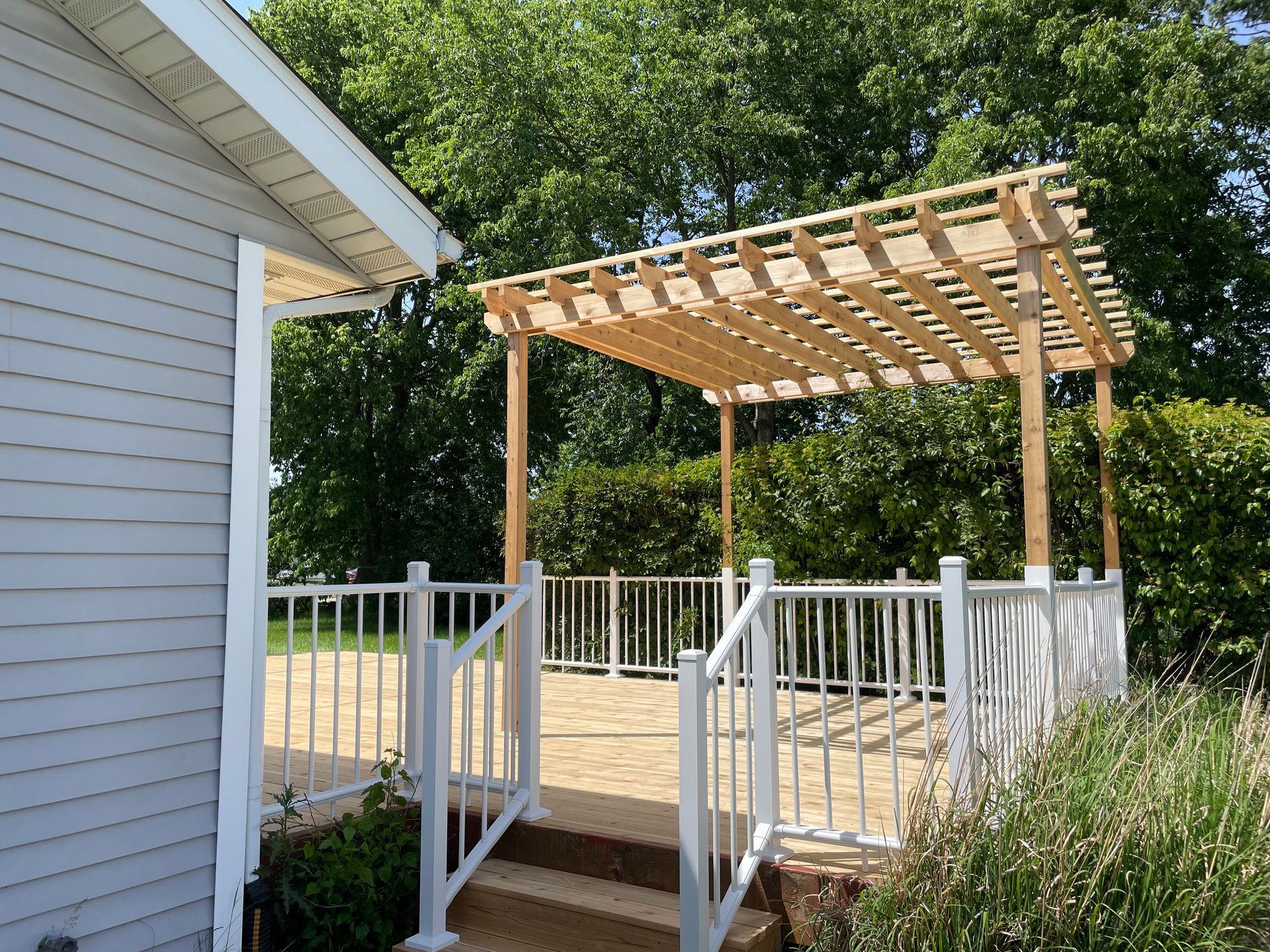 A white house with a wooden pergola over a deck