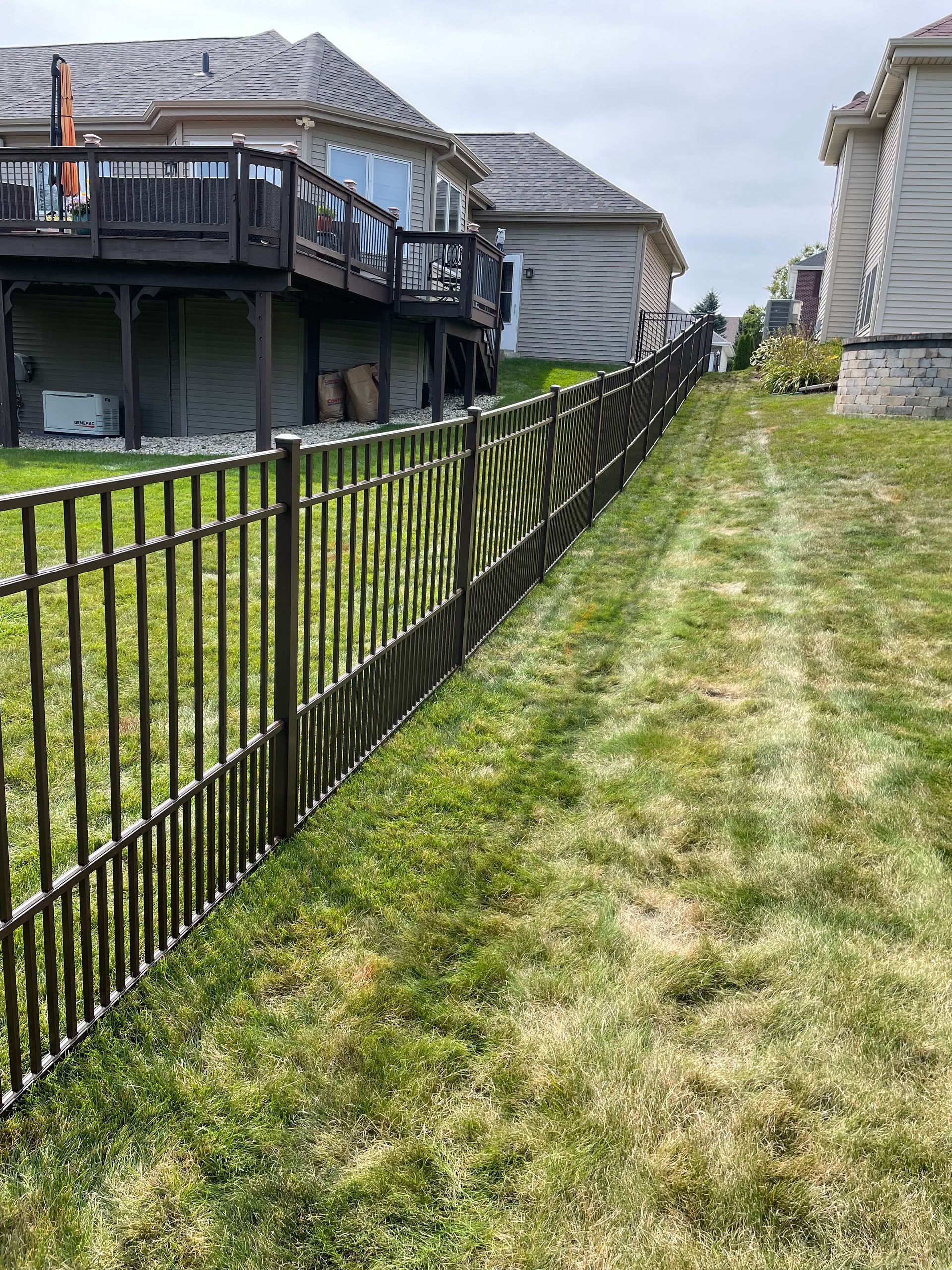A wrought iron fence surrounds a lush green yard in front of a house.