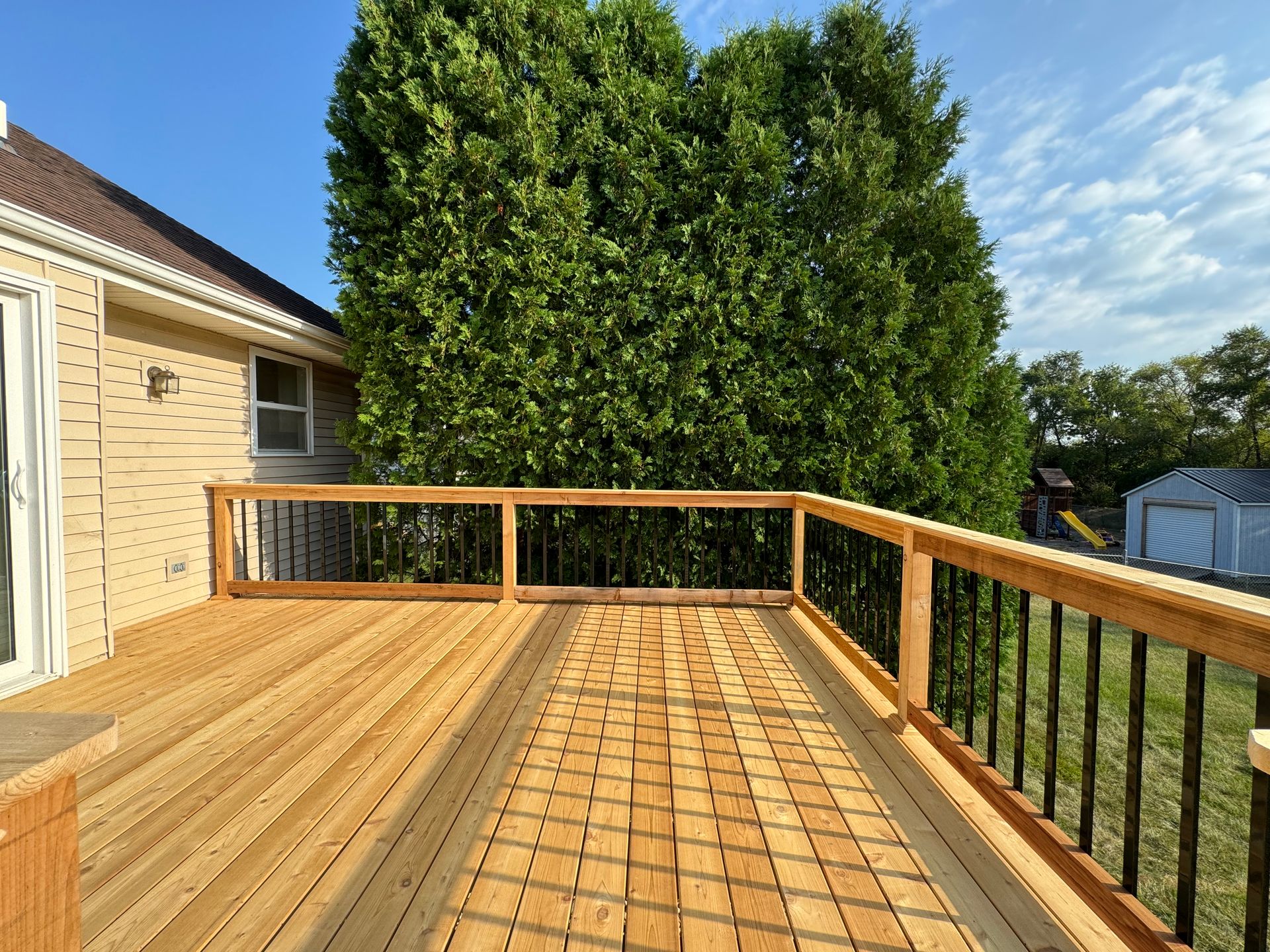 A wooden deck with a metal railing is sitting on top of a brick house.