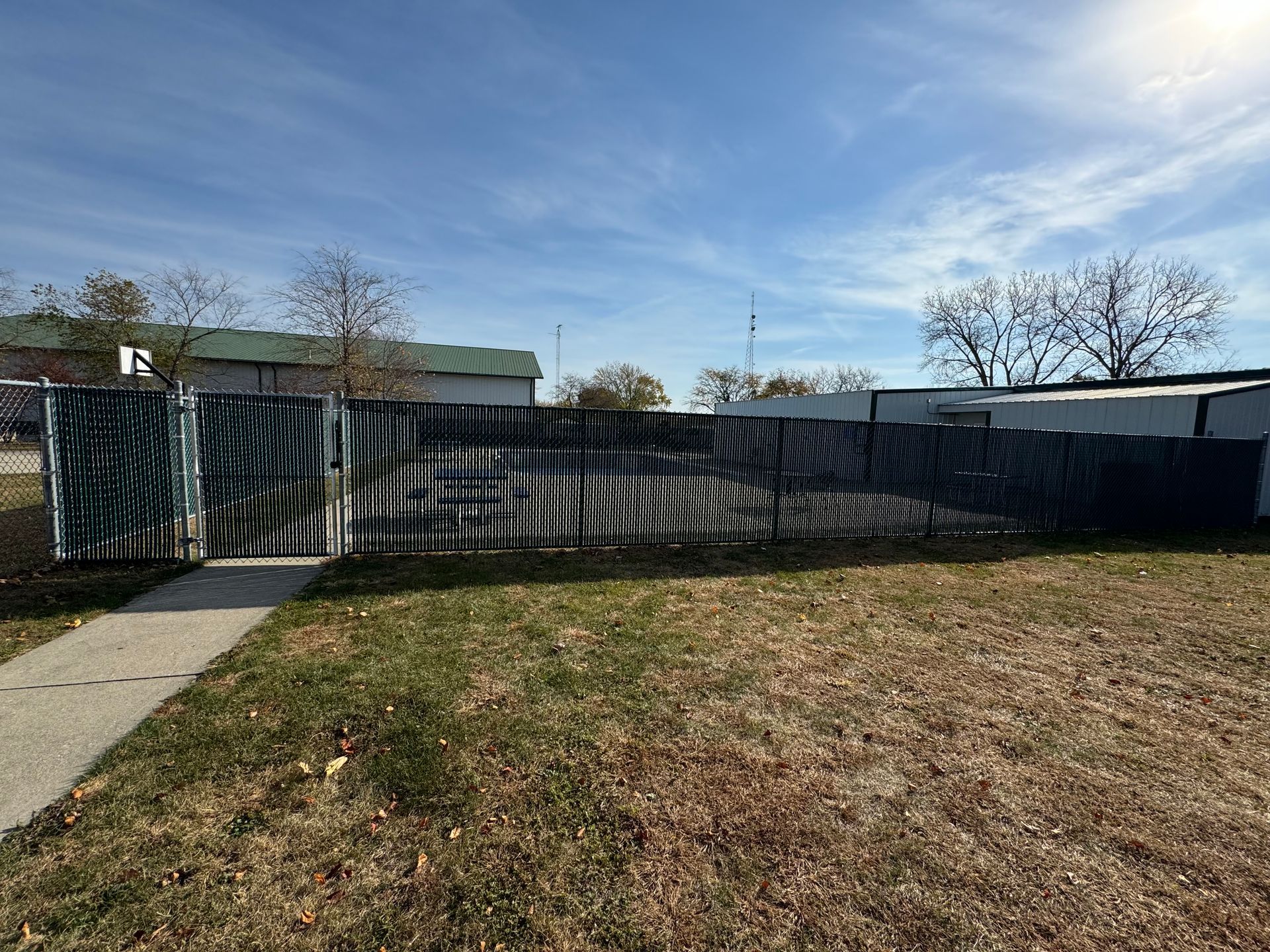 A fence is sitting in the middle of a grassy field next to a sidewalk.