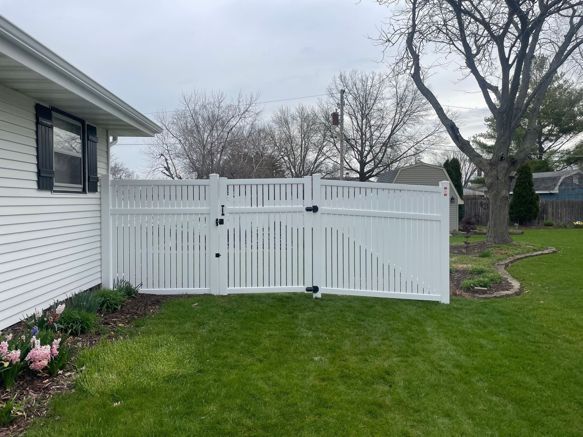 A white fence is in the backyard of a house.