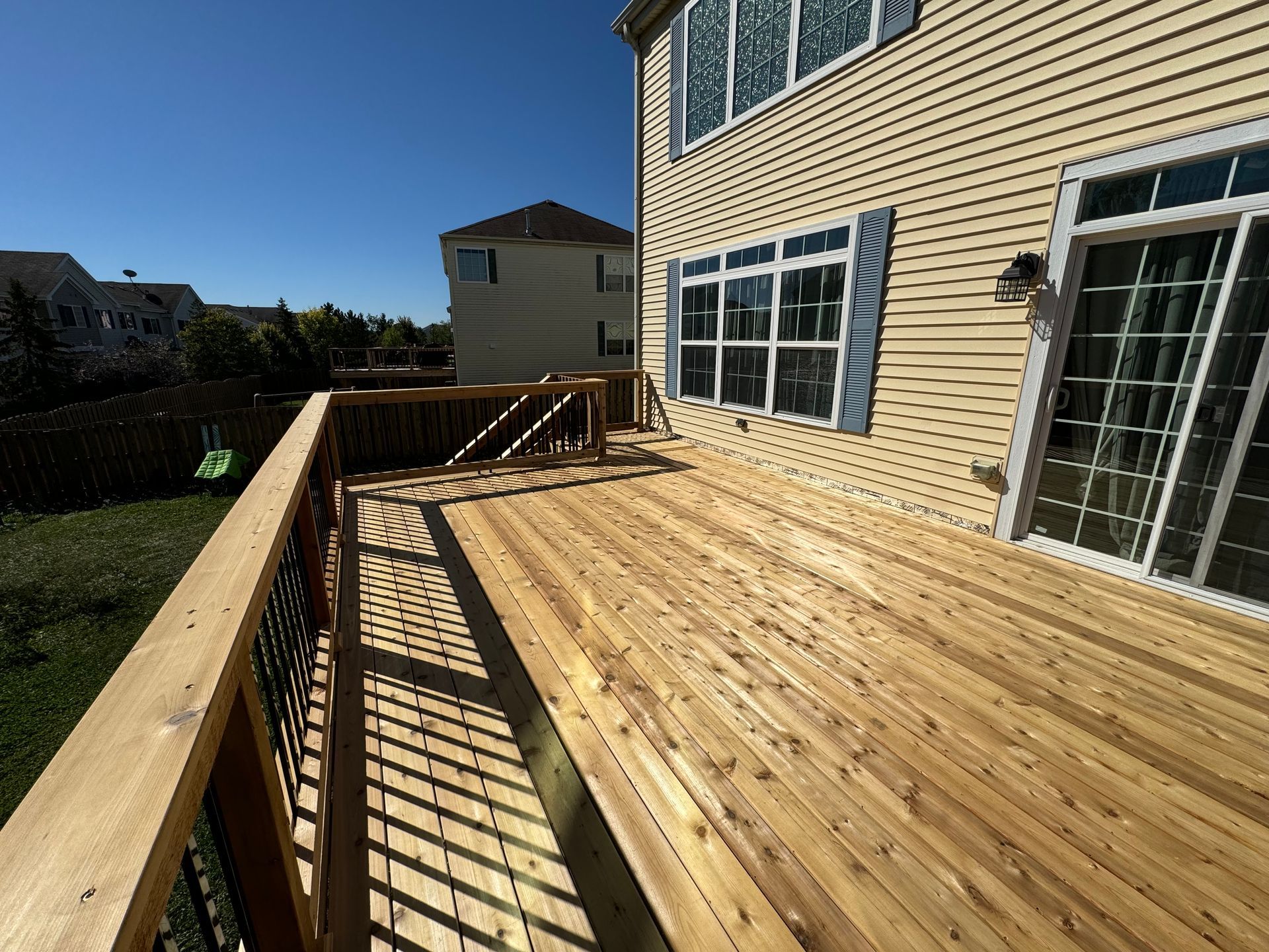 A large wooden deck is sitting in front of a house.