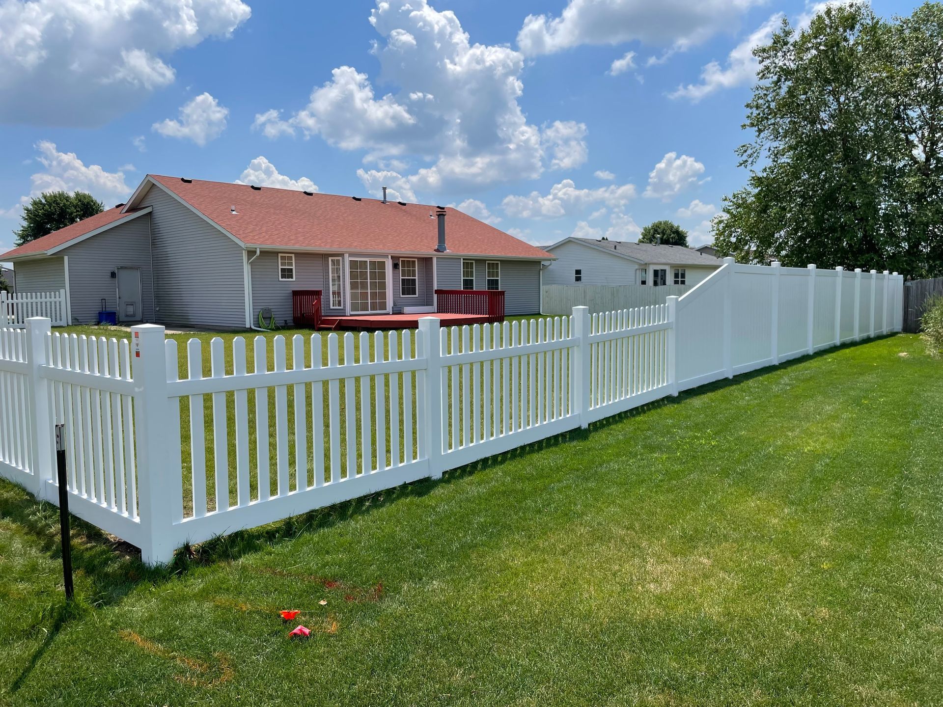 A white fence surrounds a backyard of a house.