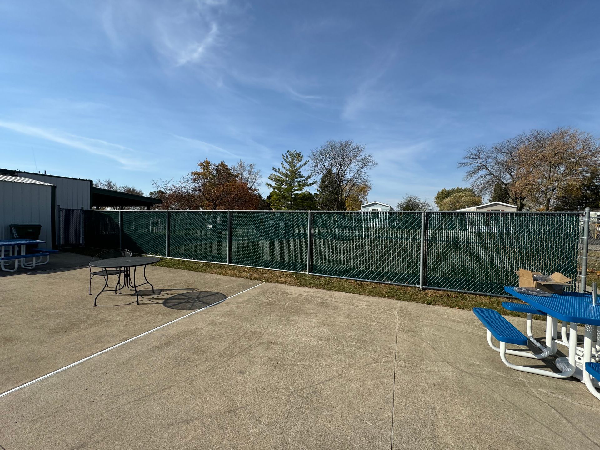 A picnic table and chairs are sitting in front of a chain link fence.