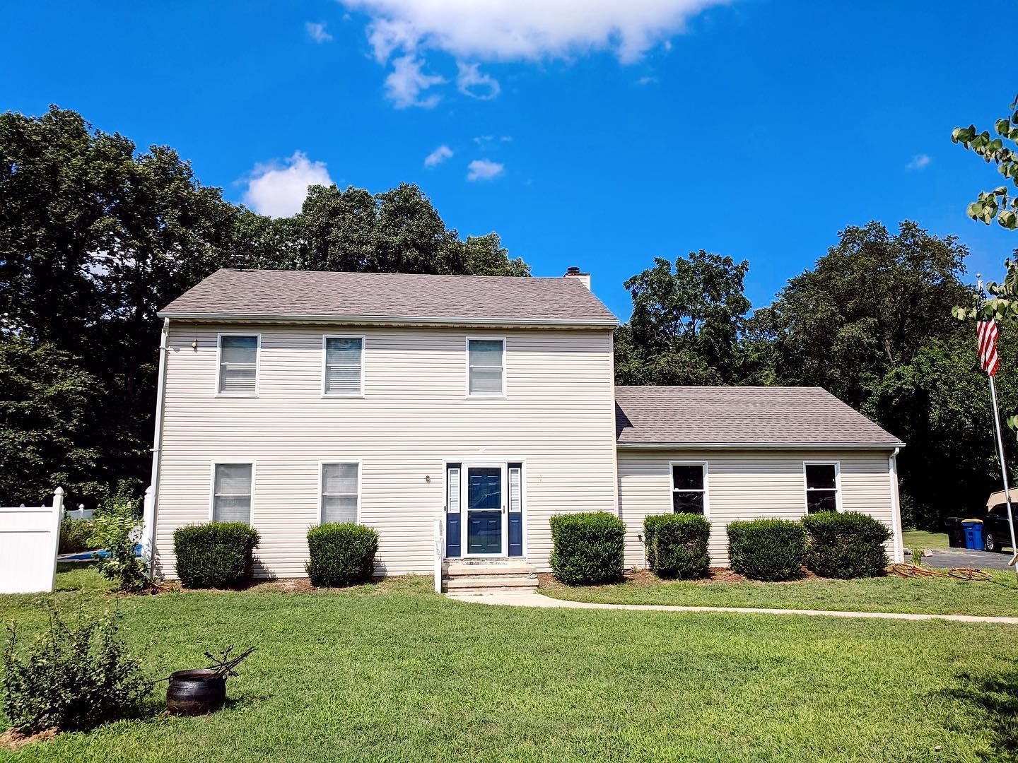 A white house with a gray roof is sitting on top of a lush green lawn.