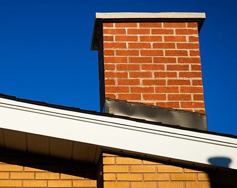 A brick chimney is sitting on top of a brick building.