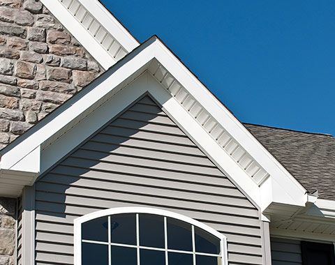 The roof of a house with a window and a brick wall.