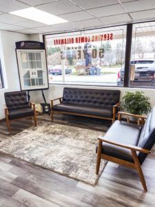 A waiting room with a couch , chairs and a rug.