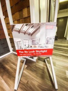 A sign that says `` the no leak skylight '' is sitting on a white easel.