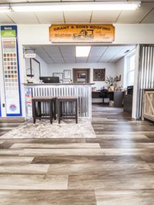 A room with a wooden floor and a sign that says grant & sons roofing.