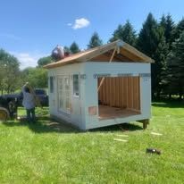 A small house is being built in a grassy field.
