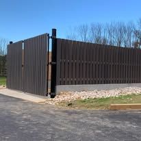 A wooden fence with a gate is sitting next to a road.