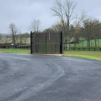 A fence is sitting on the side of a road next to a field.