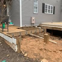 A wooden deck is being built in front of a house.