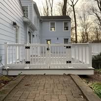 A white deck with a fence in front of a house.