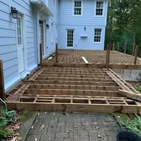A wooden deck is being built in front of a house.