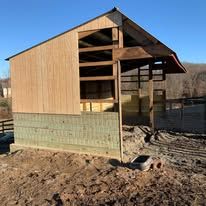 A small wooden house is sitting in the middle of a dirt field.