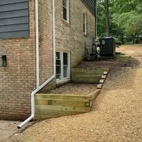 A brick house with a wooden deck and a drain pipe on the side of it.