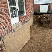 A brick building with a hole in the ground in front of it.