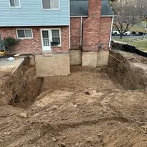 A large pile of dirt is in front of a brick house.