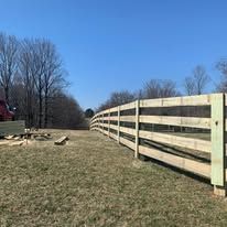 A wooden fence is sitting in the middle of a grassy field.