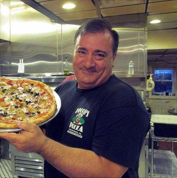 Owner holding pizza