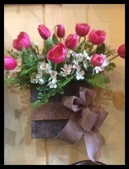 A box of pink flowers with a brown bow