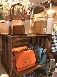 A display of handbags and wallets on a wooden crate.