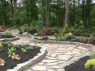 A stone walkway in a garden with trees in the background