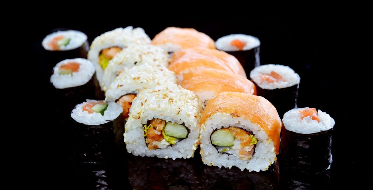 Sushi rolls, close-up on black background. Various rolls with rice, salmon, and seaweed.