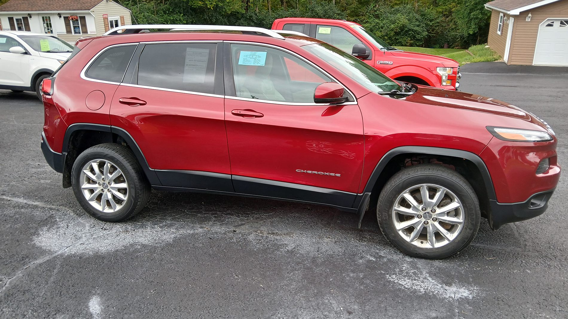 Red SUV parked in a driveway with a red car behind it on a rainy day.