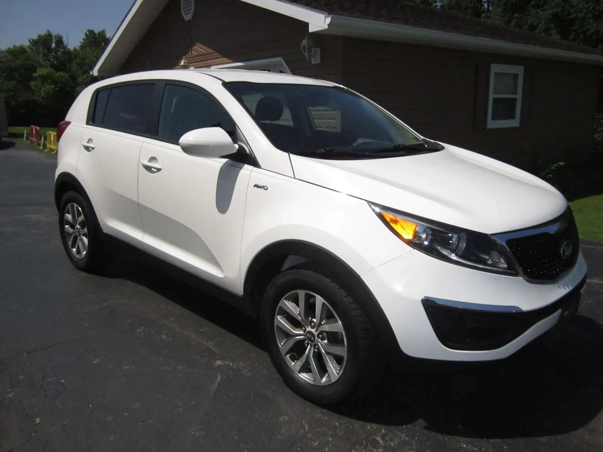 White SUV parked in a driveway in front of a house with dark trim
