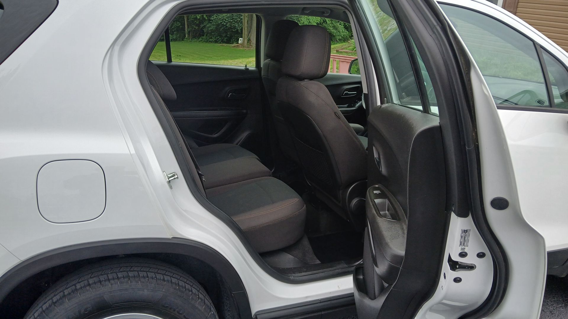 Open rear door of a gray sedan, showing the back seat and interior.